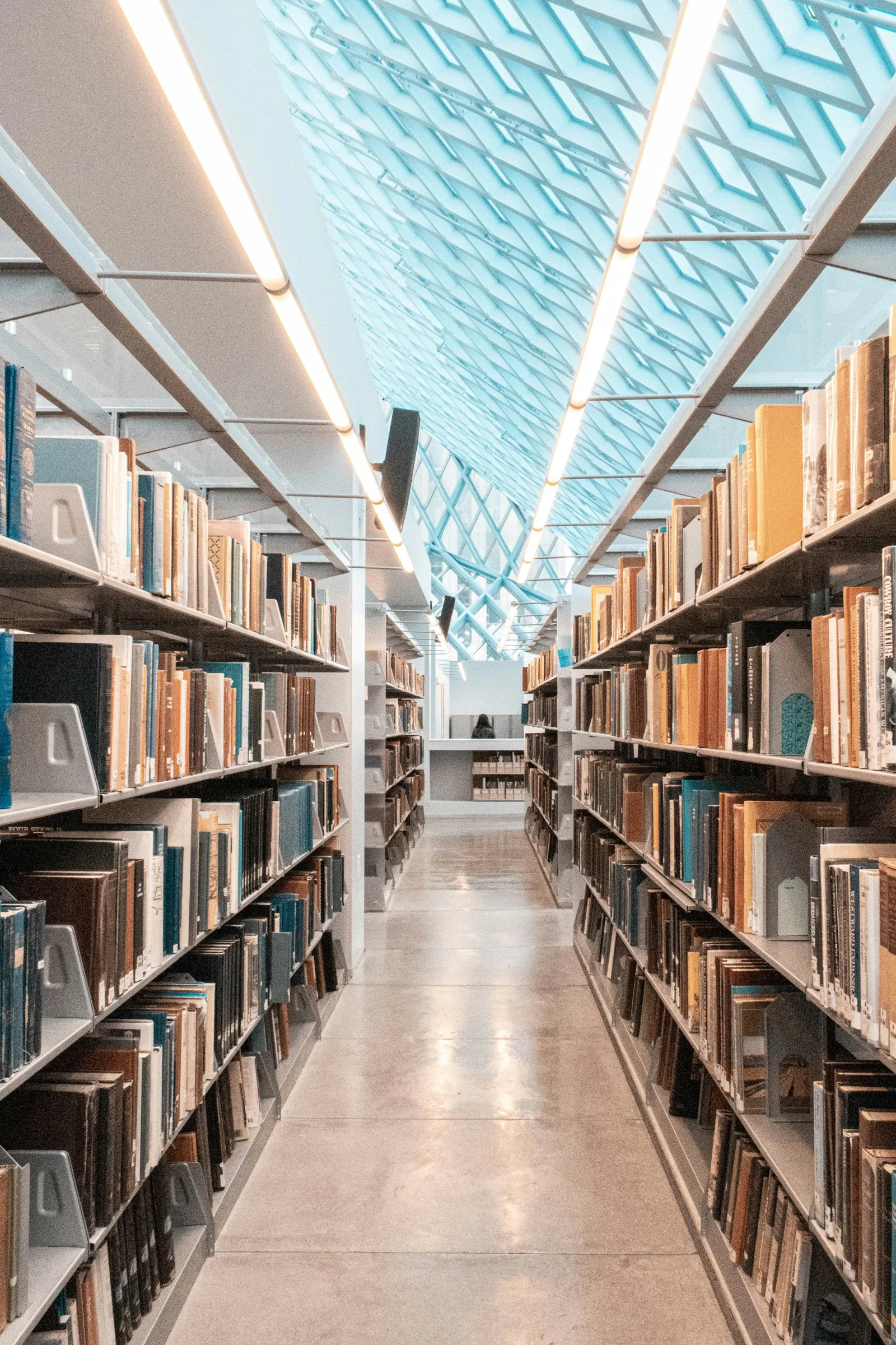 Long aisle between book stacks under a glazed roof