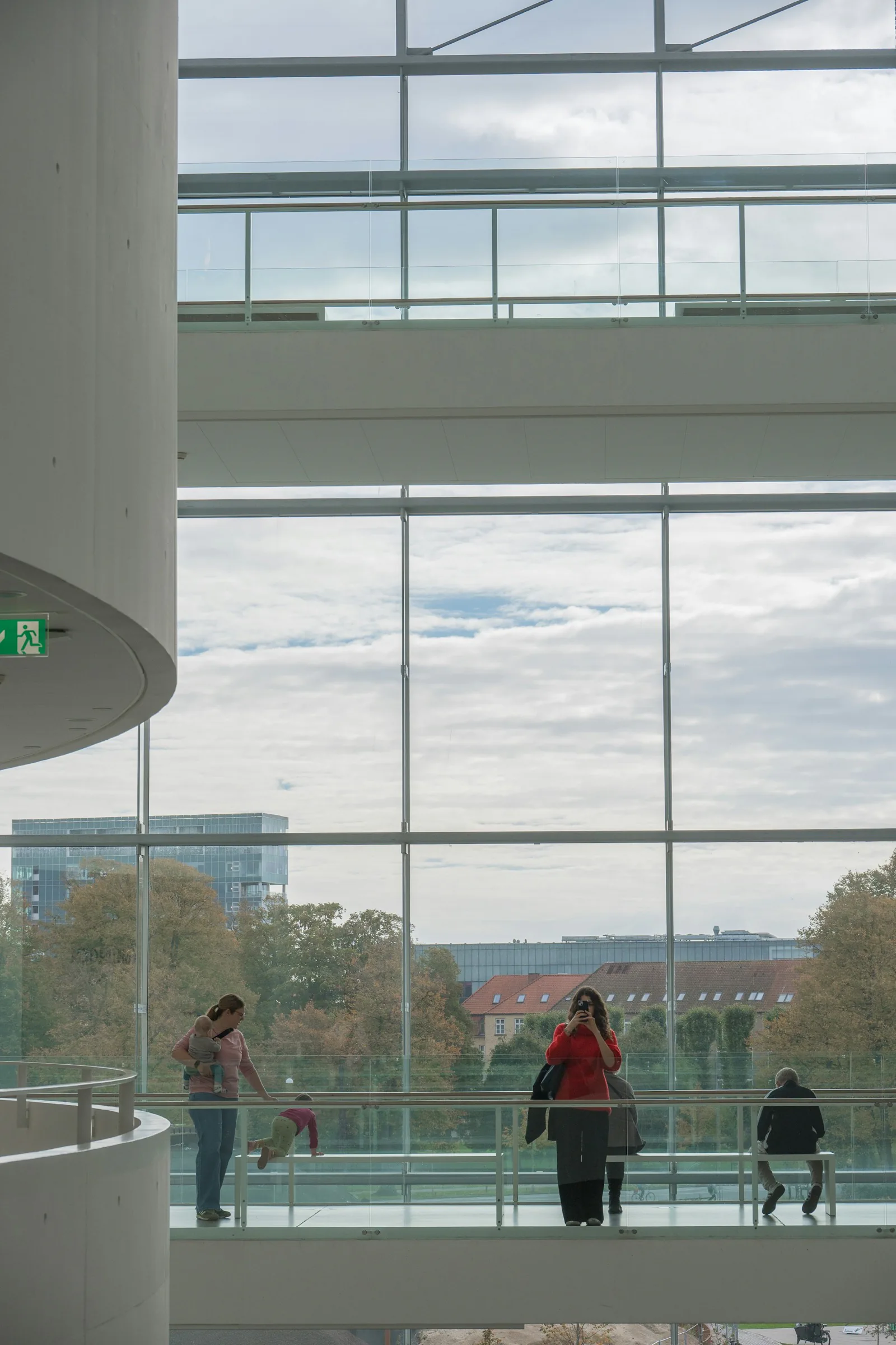 People on a gallery overlooking a city through glass