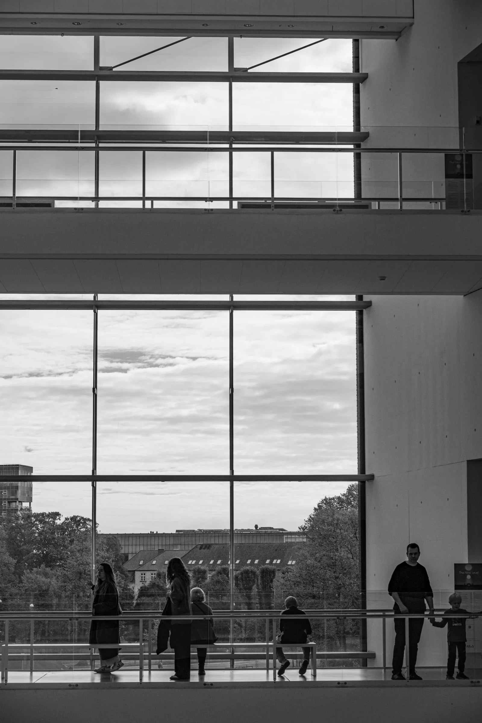 People at a tall window looking out over a city