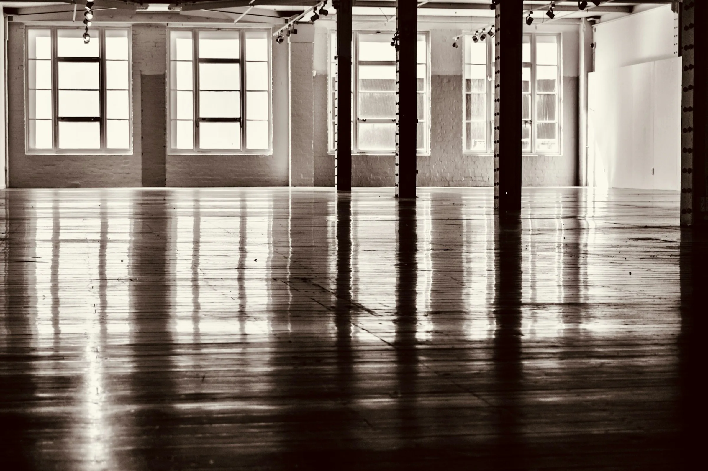 Empty industrial hall with tall factory windows reflected in a polished floor