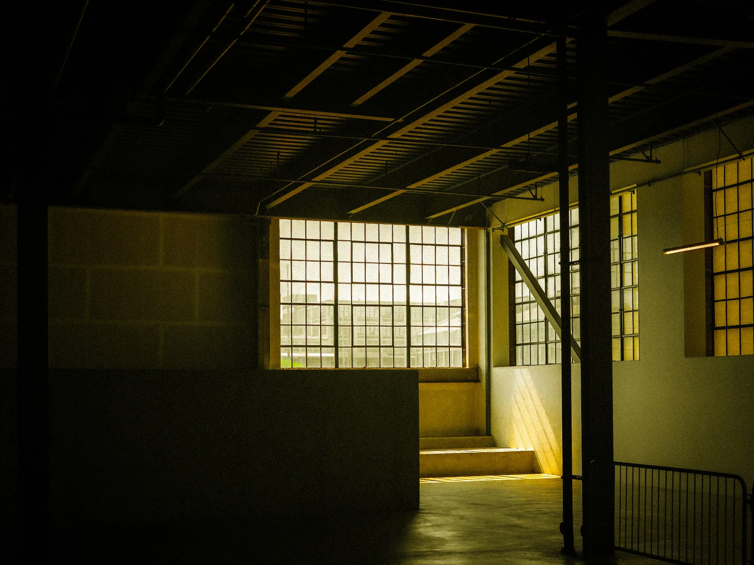 Warm light falling through factory windows onto a timber studio box